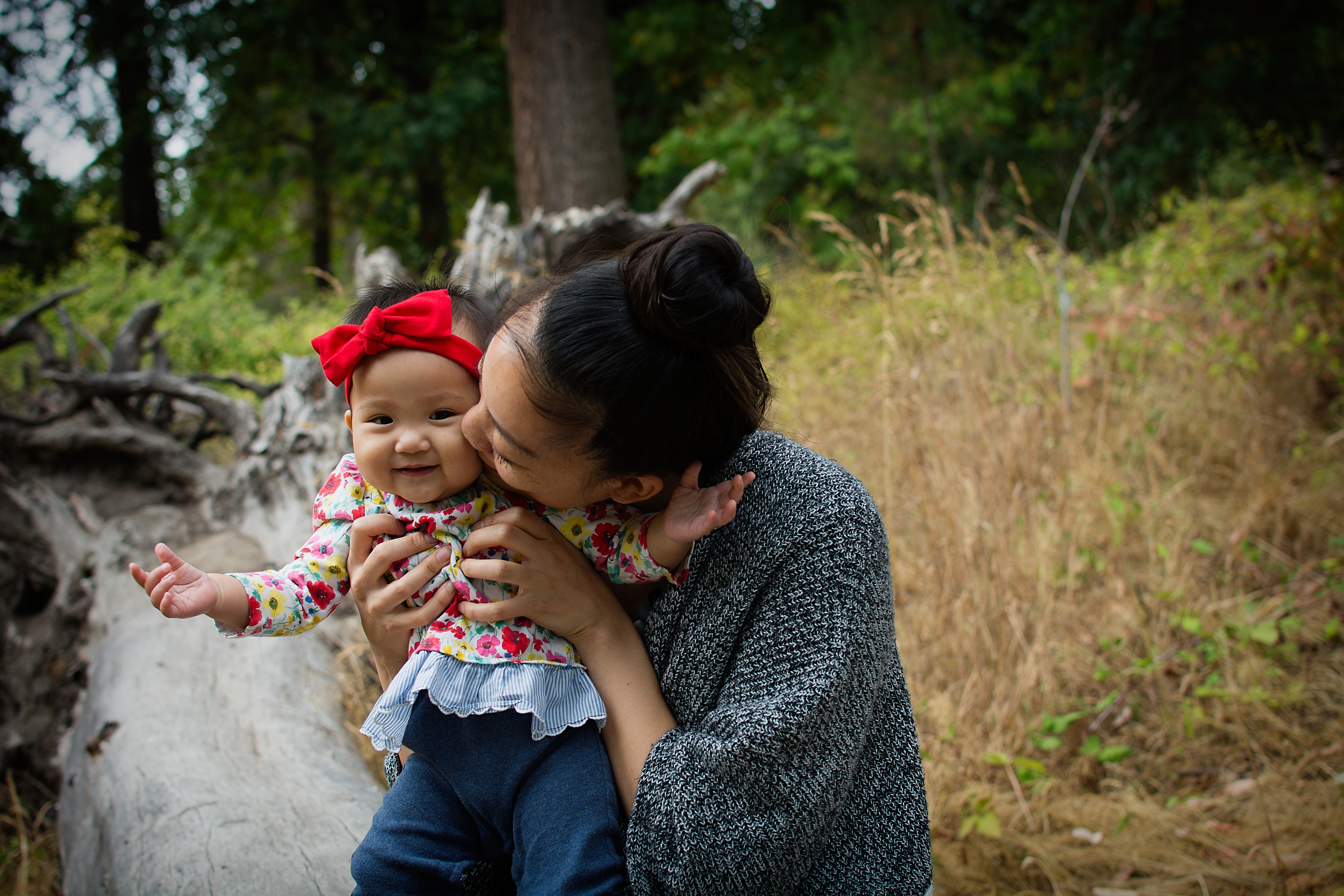 woman kissing her baby during their family photo session Seward Park in Seattle Washington