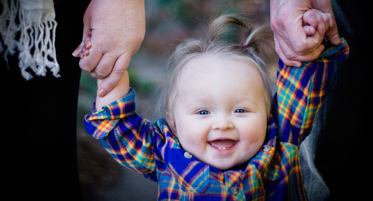 smiling little girl holding her parents hands at Seattle University
